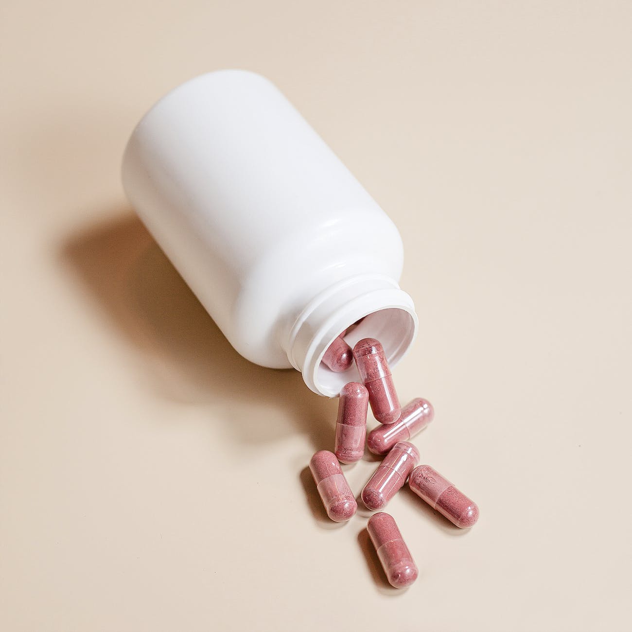 pink capsules beside plastic bottle on a surface